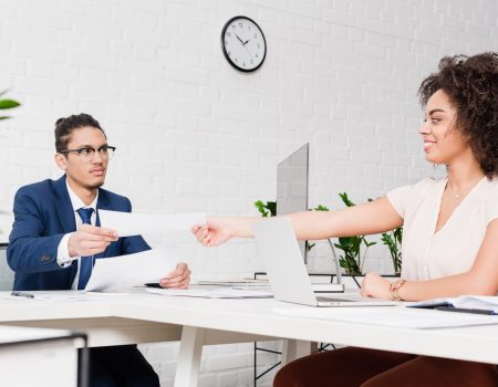 Businesswoman passing papers to businessman by working table