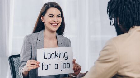 Selective focus of african american recruiter and employee smiling and holding placard with looking